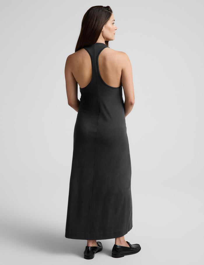 Pregnant woman wearing a black racerback dress against a plain background.