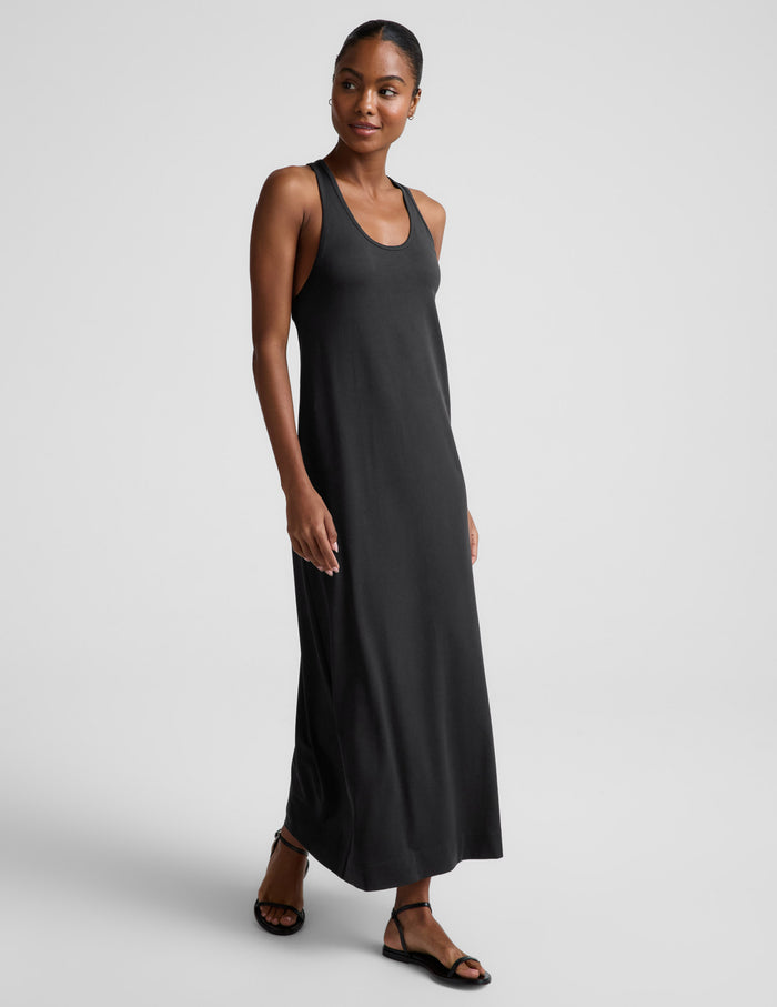 Woman wearing a black sleeveless racerback maxi dress on a light gray background.