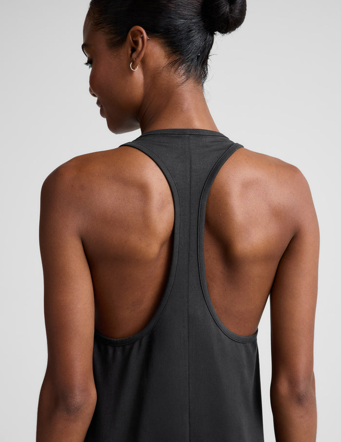 Woman wearing a black sleeveless racerback maxi dress on a light gray background.
