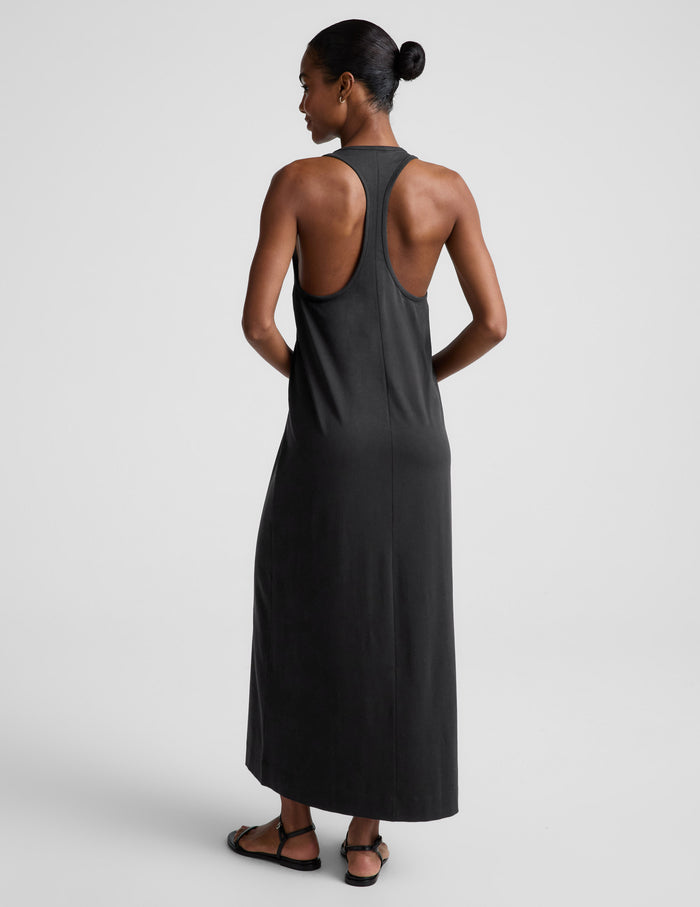 Woman wearing a black sleeveless racerback maxi dress on a light gray background.