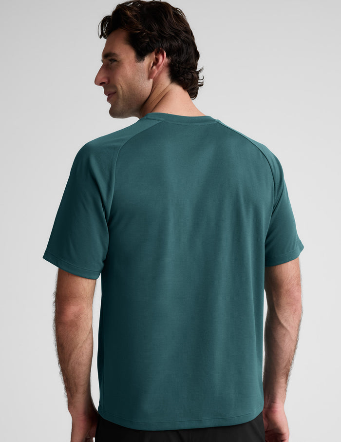 Man wearing a teal t-shirt against a plain background.