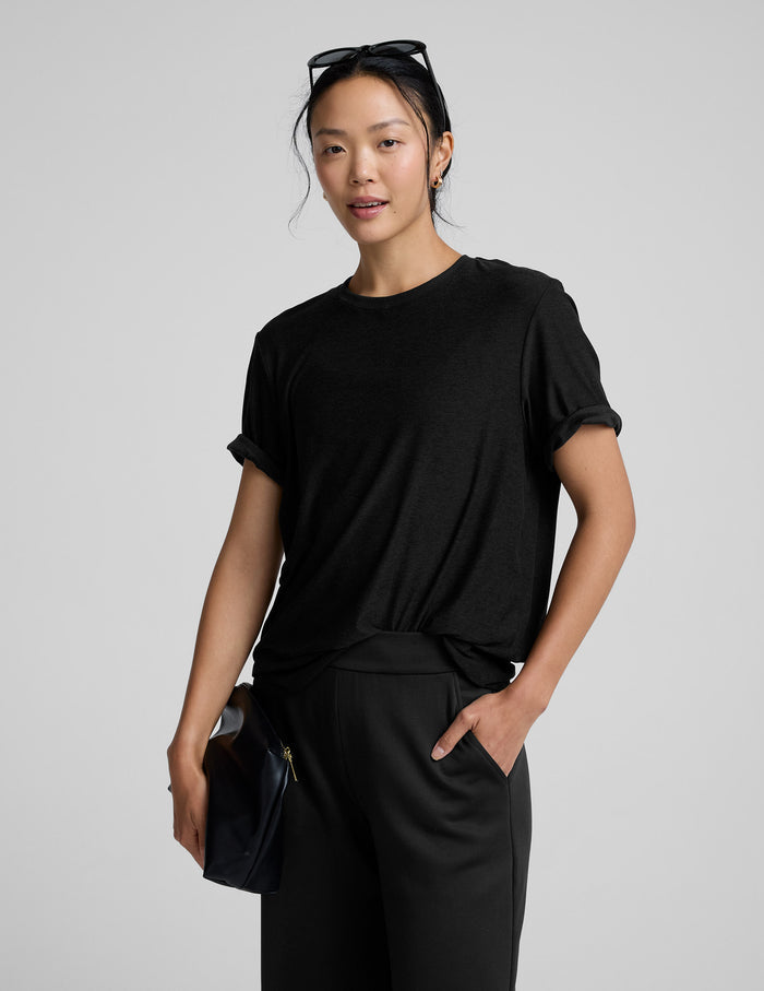 Person wearing a black t-shirt and black pants on a gray background.