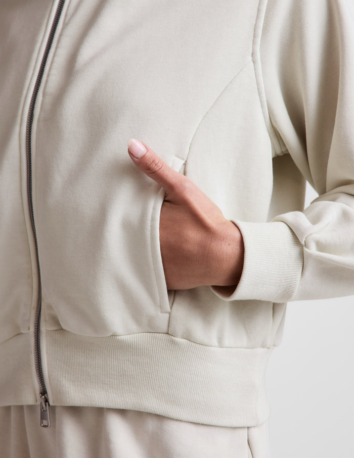 Woman wearing a white sweatshirt and shorts on a plain background.