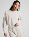 Woman wearing a white crew-neck and shorts against a plain background.