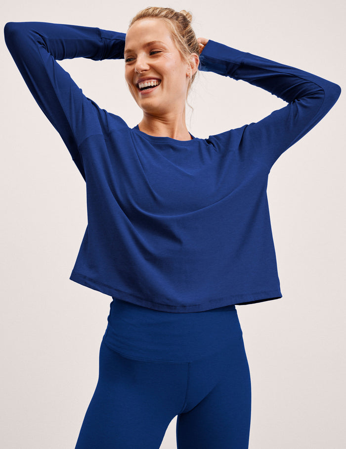Woman wearing a blue long-sleeve top and leggings against a light background.