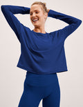 Woman wearing a blue long-sleeve top and leggings against a light background.