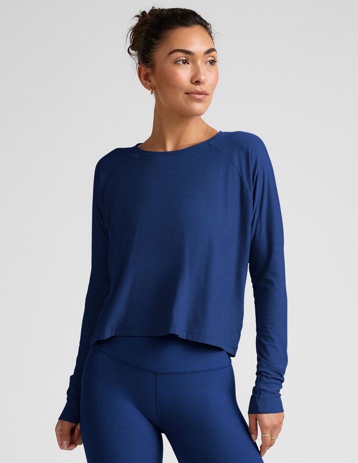 Woman wearing a blue long-sleeve top and leggings against a light background.