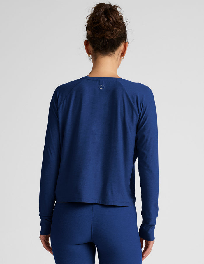Woman wearing a blue long-sleeve top and leggings against a light background.