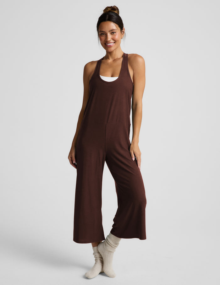 Woman wearing a brown jumpsuit on a white background.