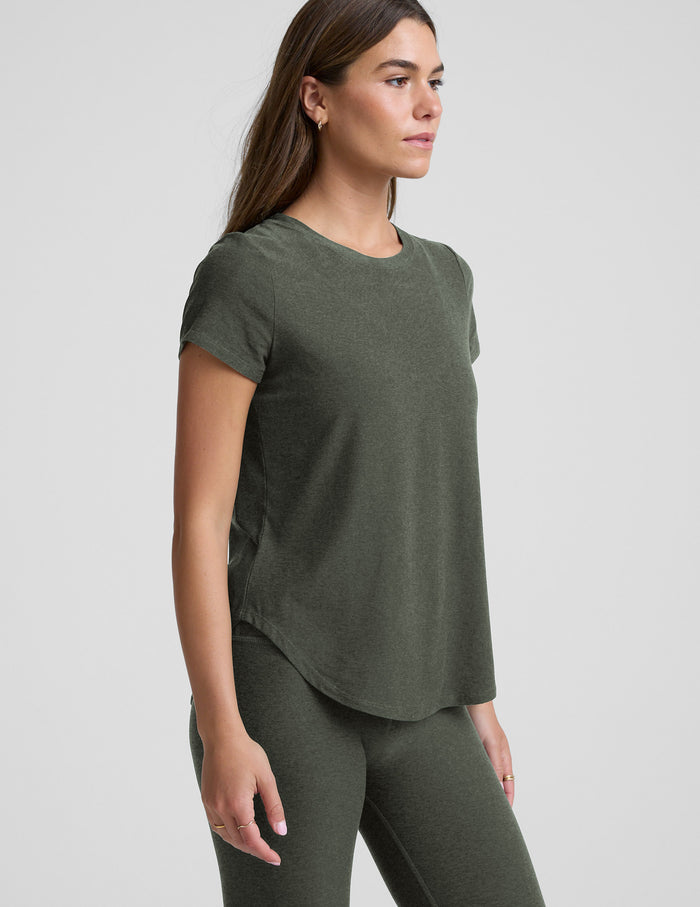 Woman wearing a green t-shirt and leggings set on a light gray background.