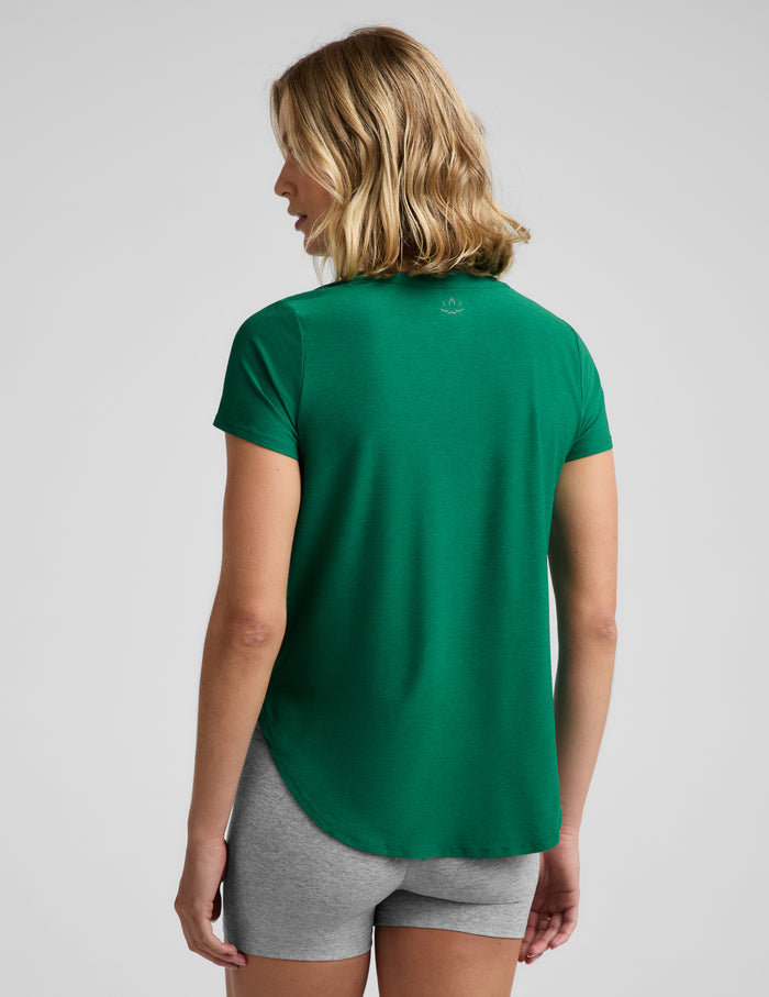 Woman wearing a green short sleeve t-shirt and gray 3" biker shorts against a plain background.