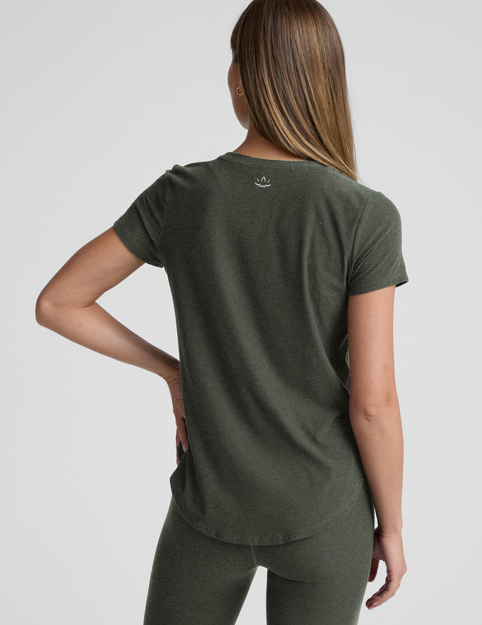 Woman wearing a green t-shirt and leggings set on a light gray background.