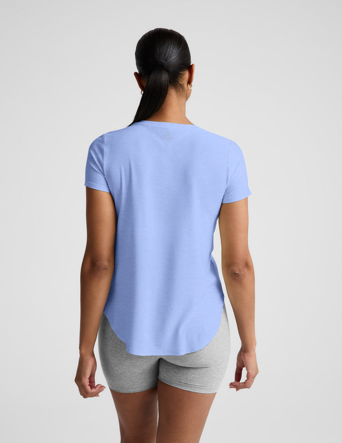 Woman wearing a light blue t-shirt and gray biker shorts against a plain background.