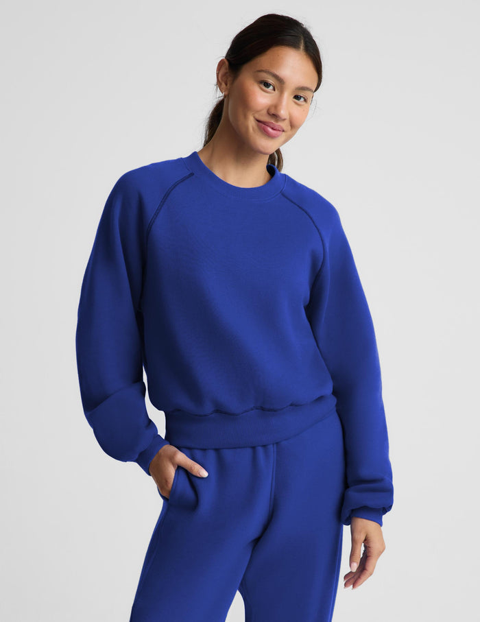 A woman modeling a matching royal blue sweatshirt and jogger pants set against a light gray studio background.