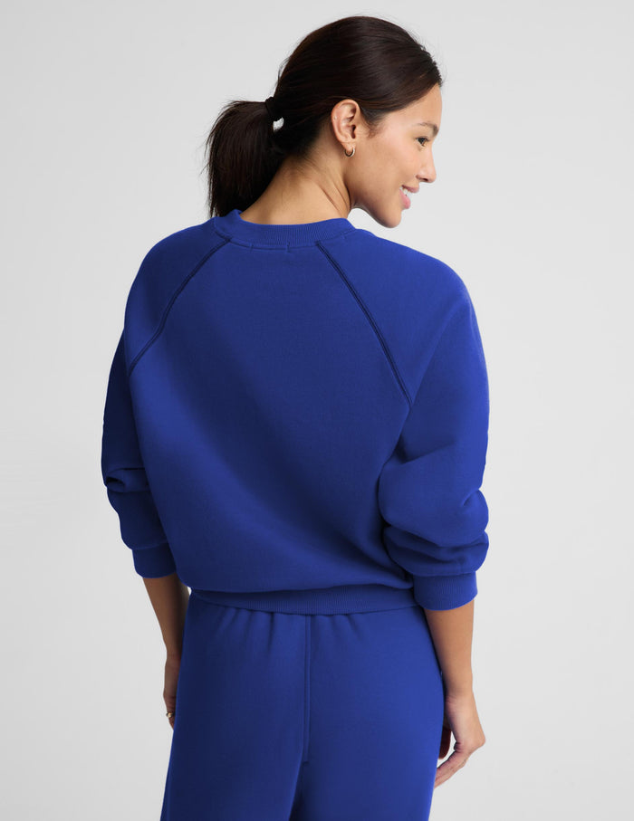 A woman modeling a matching royal blue sweatshirt and jogger pants set against a light gray studio background.