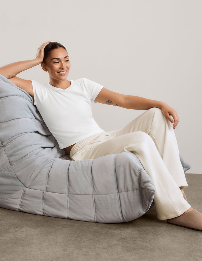 A woman modeling a white short-sleeve cropped top and off-white wide-leg sweatpants against a neutral studio backdrop.