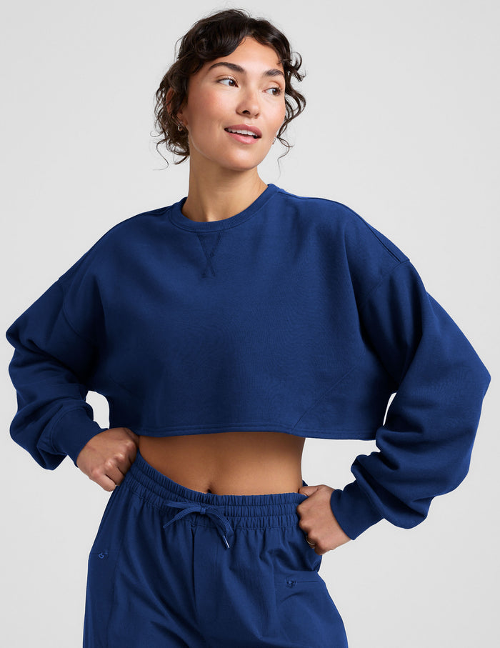 Woman wearing a blue sweatshirt and sweatpants on a plain background.