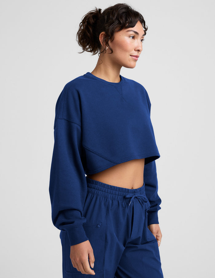 Woman wearing a blue sweatshirt and sweatpants on a plain background.