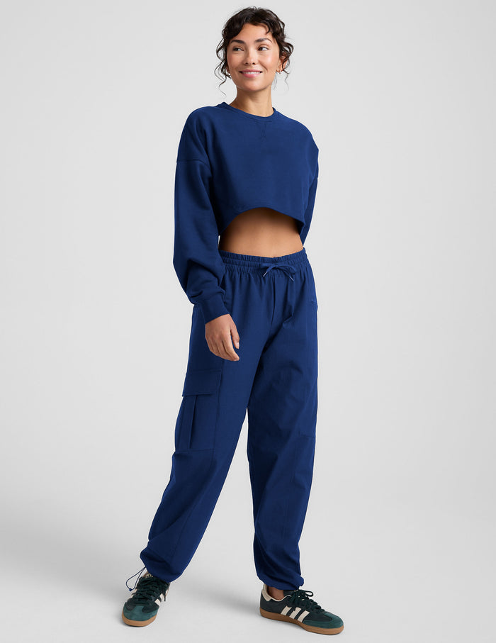 Woman wearing a blue sweatshirt and sweatpants on a plain background.