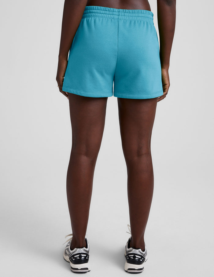 Back view of the blue LuxeFleece Sweat Short showing a relaxed fit and elastic waistband on a model.