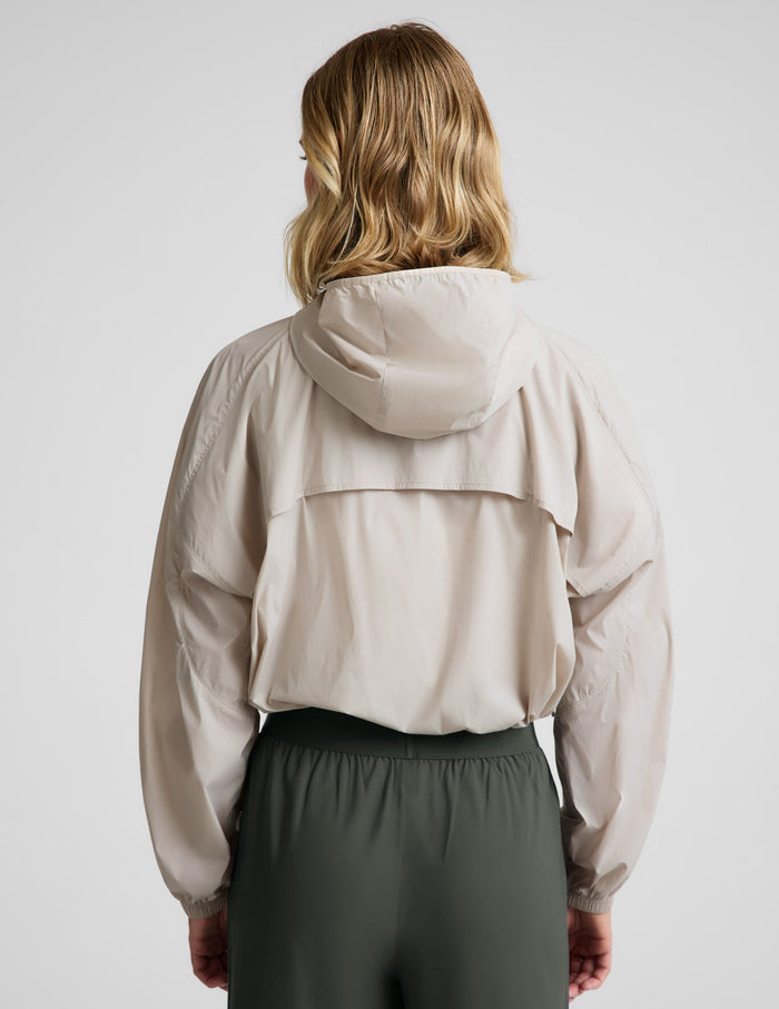 Woman wearing a beige jacket and green pants against a plain background.