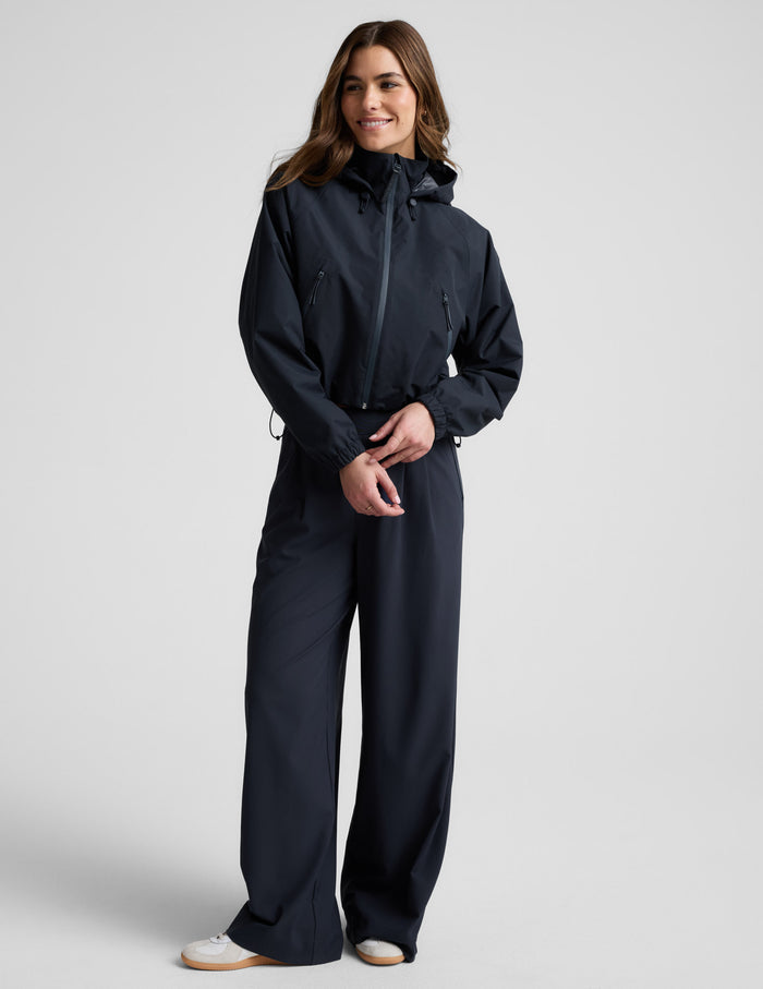Woman wearing a blue hooded jain jacket and pants against a plain background.