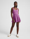 Woman wearing a purple mini dress against a plain background.