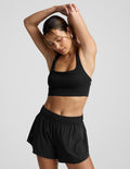 Woman wearing a black sports bra and shorts against a plain background.