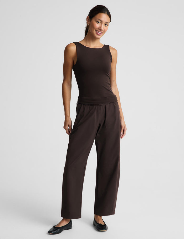 A woman modeling a dark brown sleeveless tank top and matching dark brown pants against a light gray studio background.