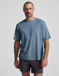 Man wearing a blue cotton t-shirt and gray shorts against a plain background.
