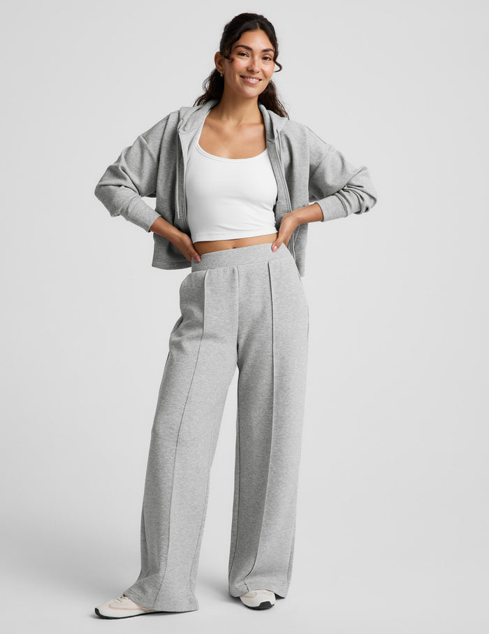 Woman wearing Gray SoftSpring Wide Leg Pant 29"™ with pintuck folds, paired with a white tank top and matching gray hoodie.