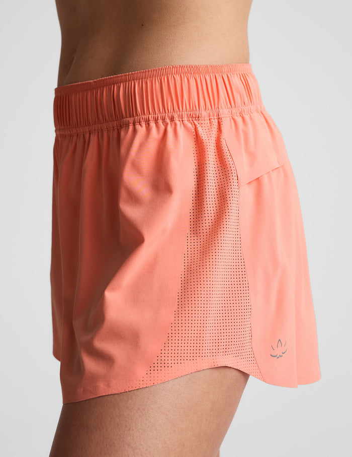 Woman wearing Peach Solemate™ 2.5" Short, side profile view, featuring perforated side panels and elastic waistband.