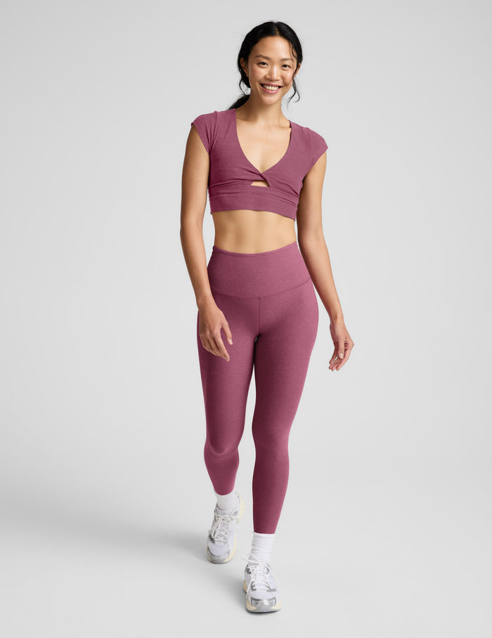 Woman wearing a mauve athletic outfit on a light gray background.
