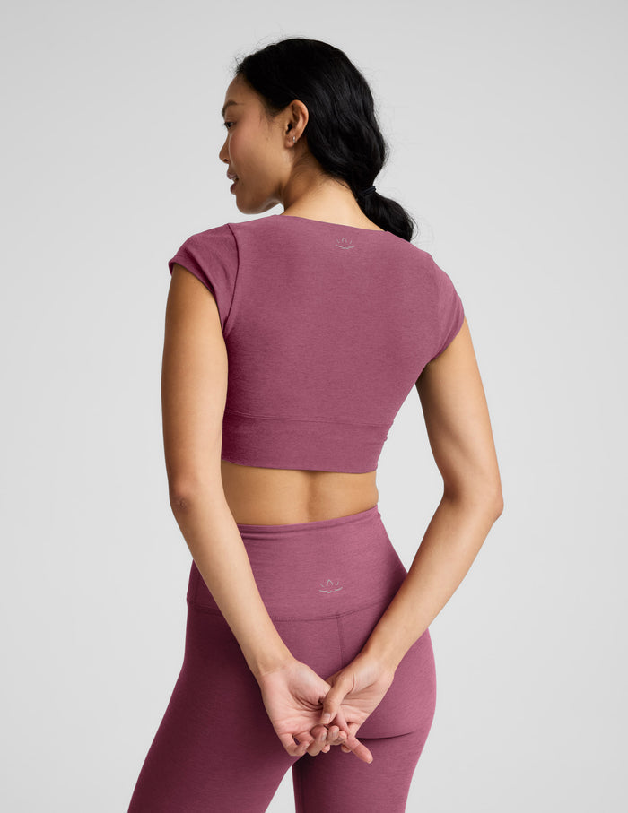 Woman wearing a mauve athletic outfit on a light gray background.