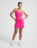 Model in fuchsia Spacedye Go Pocket Skirt with high drawstring waist and side slits, paired with a matching crop tank top.