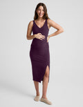 Woman wearing a purple dress with a slit on a light gray background