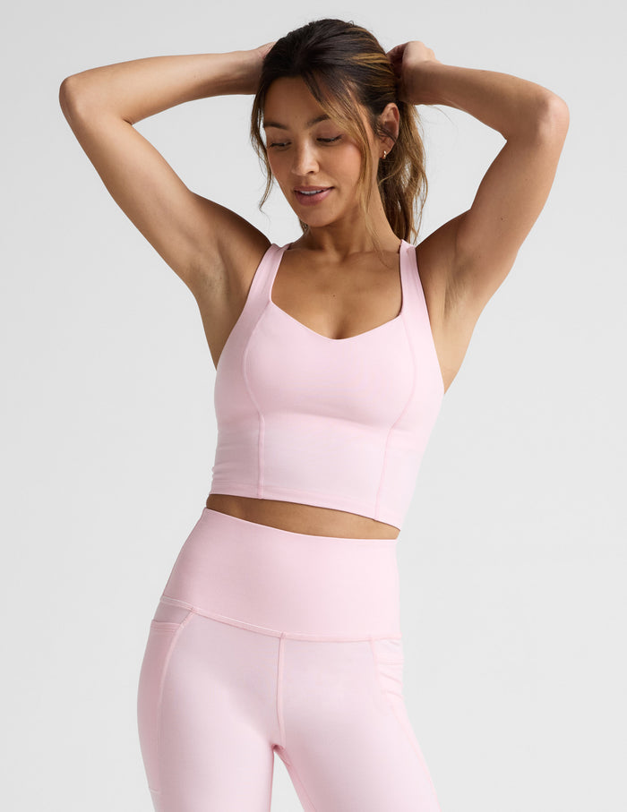 Woman wearing a pink athletic outfit on a light gray background