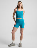Woman wearing Capri Blue Spacedye™ Keep Pace 3" Short paired with a matching tank top and grey sneakers.