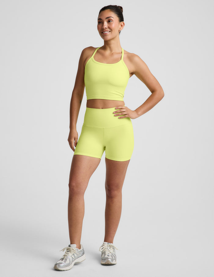 Woman wearing Yellow Spacedye™ Keep Pace 3" Short with high waistband, paired with a matching tank and white sneakers.