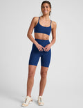 Navy marled Spacedye Keep Pace 7" Short on a smiling woman. High-waisted, mid-thigh length, snug fit athletic bike shorts.