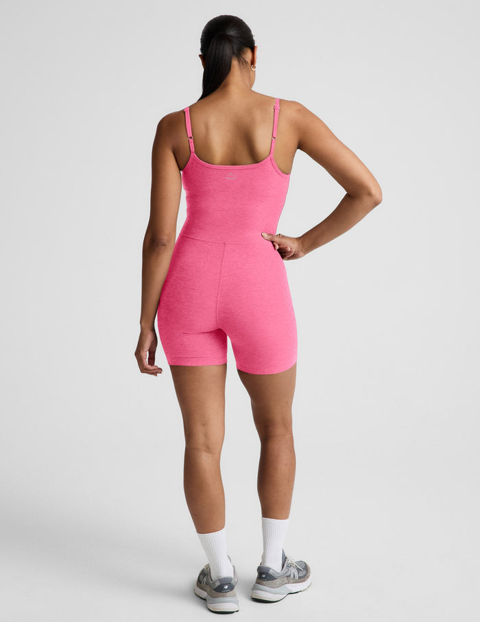 Woman wearing a pink sleeveless biker jumpsuit against a plain background.