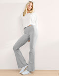 Woman wearing a white top and gray pants against a plain background.