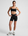 Woman wearing Black Spacedye At Your Leisure™ 5" Biker Short with overlapping waistband and matching sports bra.