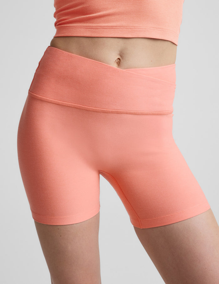 Woman wearing coral Spacedye At Your Leisure 5" Biker Short with an overlapping waistband, paired with a matching top.