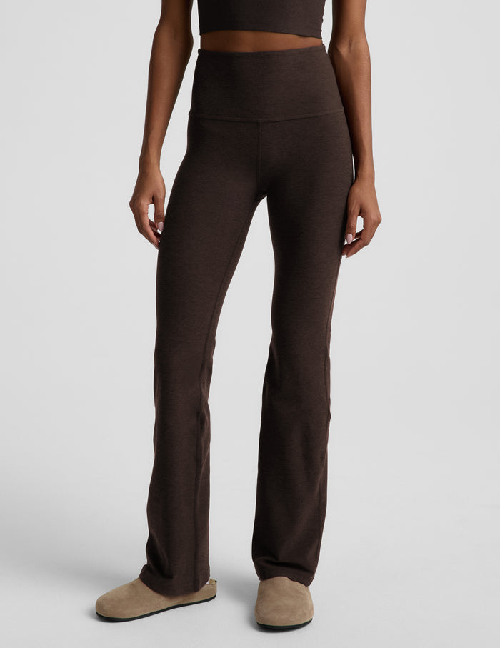Woman wearing a brown cropped tank top and brown high-waisted bootcut pants against a plain background.
