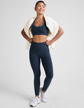 blue high-waisted midi length leggings with white piping on the side.