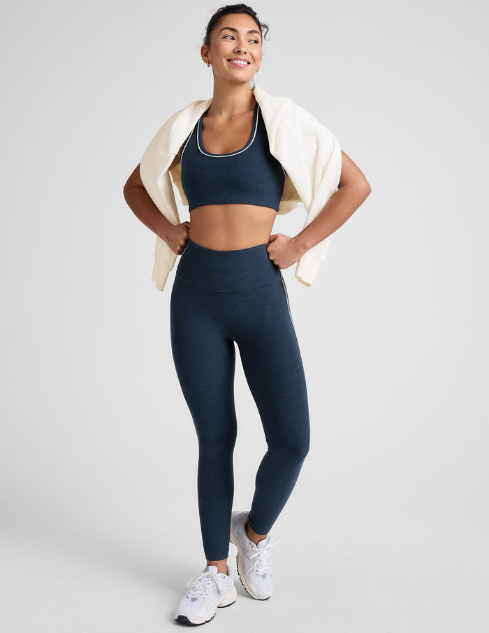 blue high-waisted midi length leggings with white piping on the side.