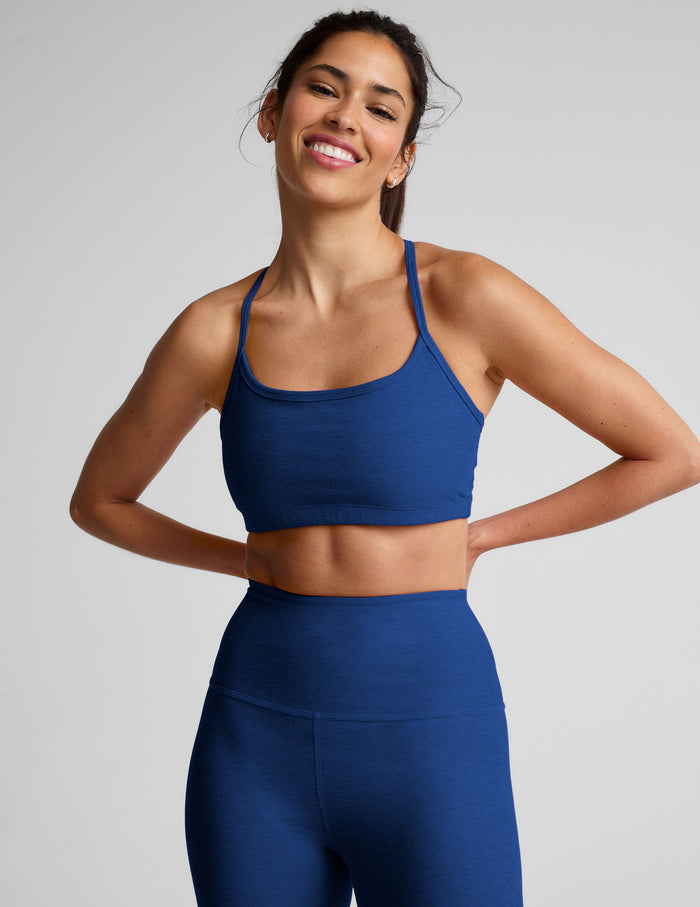Woman wearing a blue racerback sports bra and leggings on a light gray background.