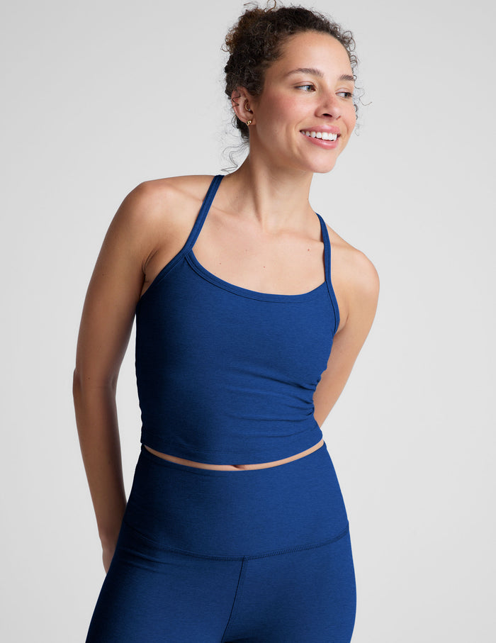Woman wearing a blue racerback cropped tank against a plain background.