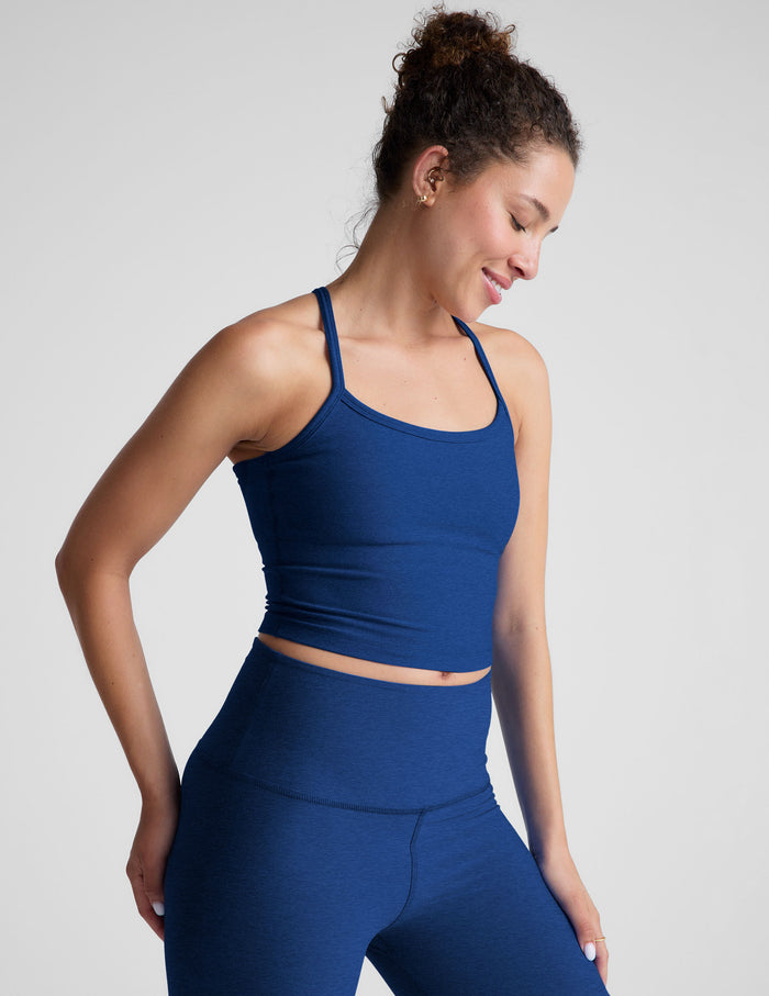 Woman wearing a blue racerback cropped tank against a plain background.